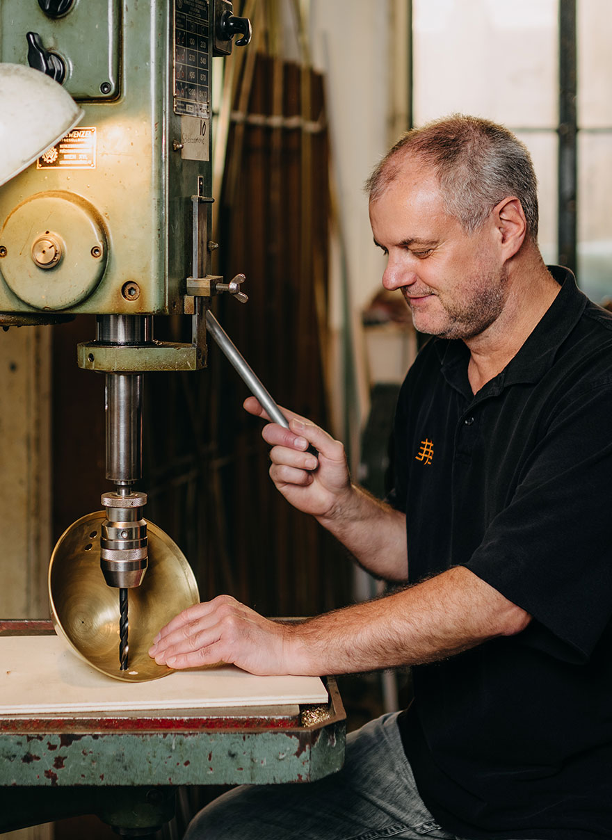 Coppersmith drilling a hole into a spun bowl